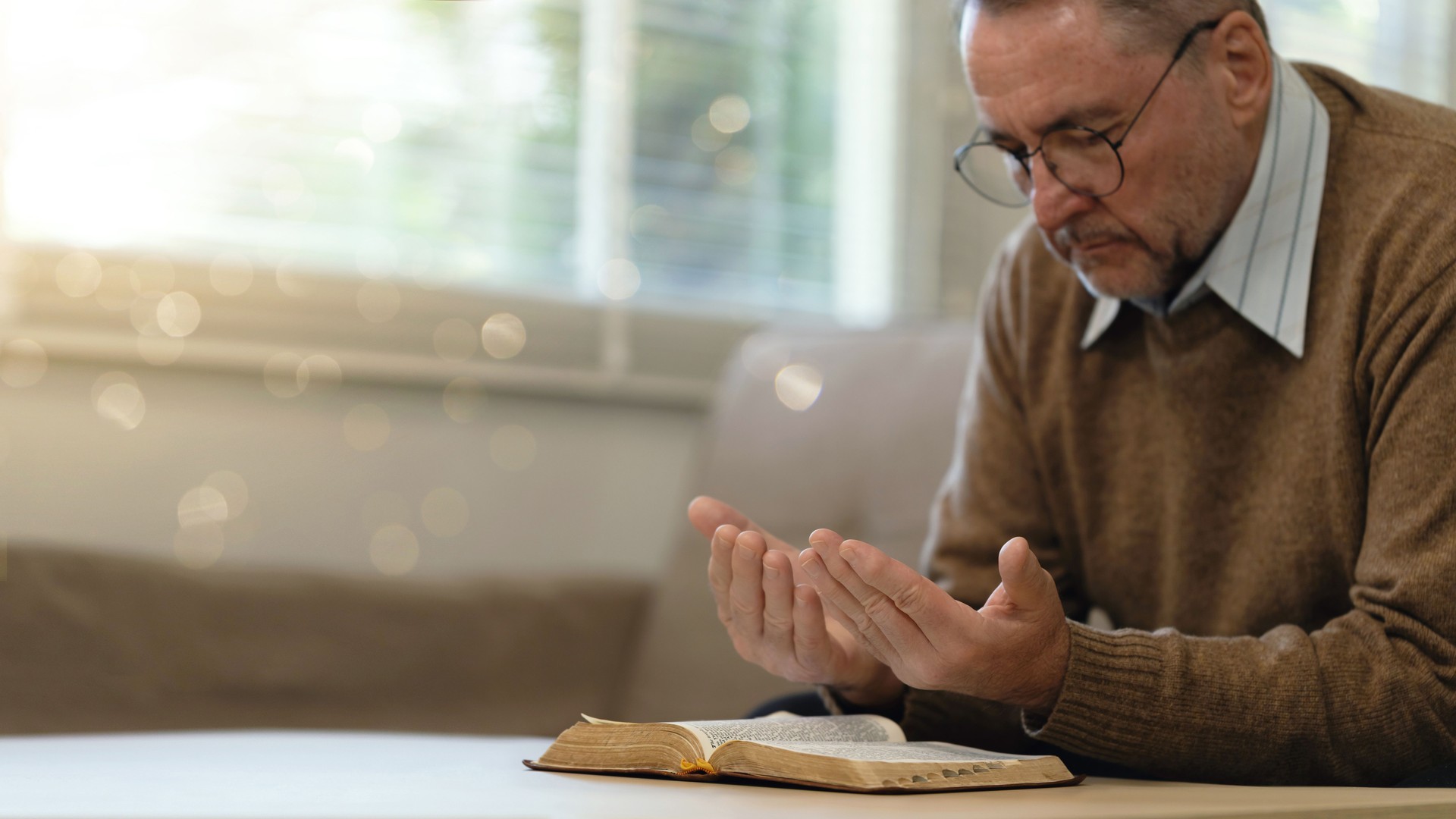 An elderly man praying to god over the Bible in the room. Old man praying to god for happiness and a better life. support or hope in Christianity or faith. Relax, meditation. holy worship. Banner